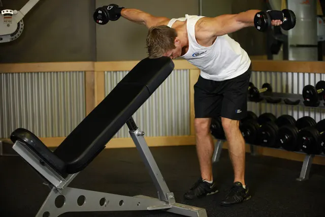 Bent Over Dumbbell Rear Delt Raise With Head On Bench, finishing position